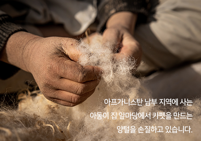 아프가니스탄 남부 지역에 사는 아동이 집 앞마당에서 카펫을 만드는 양털을 손질하고 있습니다.